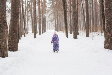 Fototapeta na wymiar Childhood and children concept - baby girl walk in the winter outdoors