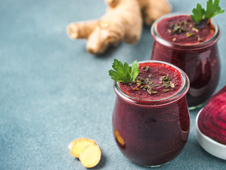 Fresh beetroot and ginger root smoothie. Beetroot smoothie in glass jar on gray table. Shallow DOF....