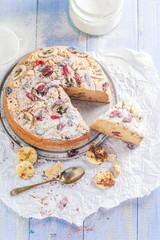 A sliced banana cake with nuts, sesame and cranberry on a wooden table
