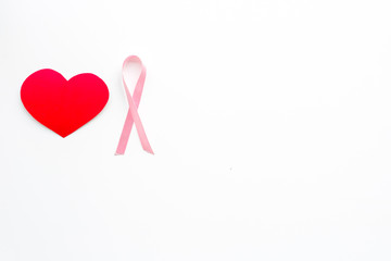 Breast cancer. Mammalogy concept. Symbolic pink ribbon near heart sign on white background top view copy space