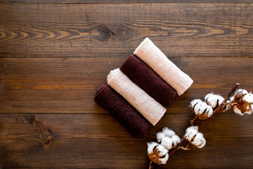 Cotton towels high quality. Set of towels twisted coil near dry cotton flowers on dark wooden background top view copy space