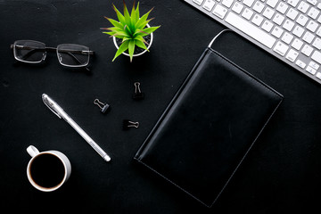 Flat lay of office desk, office workplace. Keyboard and glasses near coffee and stationery on black background top view