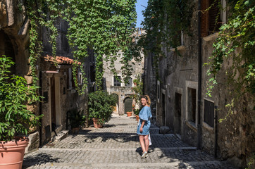Young beautiful girl during a walk through the antique streets of the old Italian city