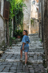 Young beautiful girl during a walk through the antique streets of the old Italian city