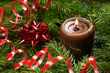 Wooden background with branches of a Christmas tree and a red candle.