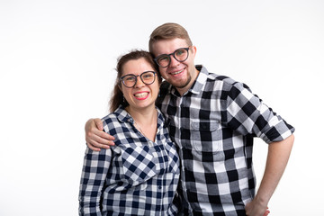Nerds, geek, bespectacled and funny people concept - funny couple in glasses are hugging on white background