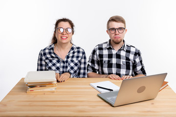 Education, students, people concept - funny couple of teens in glasses look like nerds sitting at the table