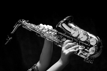 Saxophone in female hands on dark background
