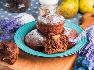 Chocolate home made baked muffins with pears and icing sugar on winter background