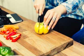 Unrecognizable woman cutting bell peppers in the kitchen.