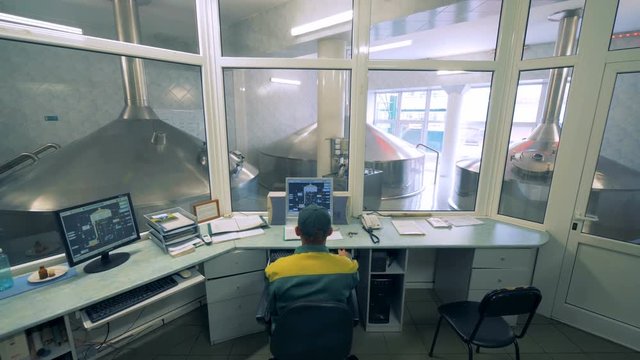Man working with computer at a brewery.