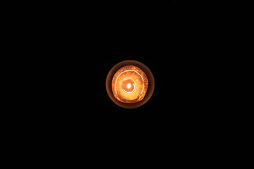 Overhead view of orange candle burning against dark black background