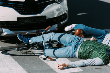 cropped shot of young cyclists lying on road after traffic collision