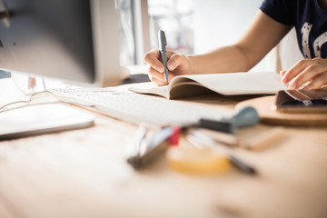 Hands of a Business woman is writing book as notepad or Take notes on Her wooden table desk  ....