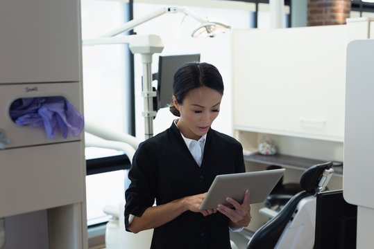 Female dentist using digital tablet in dental clinic