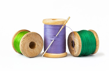 Threads on wooden spools and sewing needle.