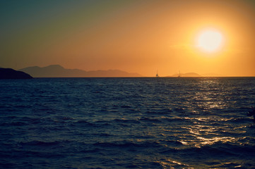 Sunset on the Turkish coast of the Aegean Sea. View of the island. Orange sky and blue sea.