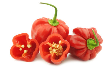 spicy hot red habanero peppers and a cut one on a white background - obrazy, fototapety, plakaty