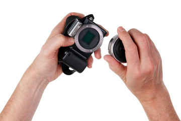 An elderly man photographer replace the lens on his no name system camera