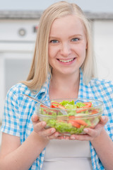 Obraz na płótnie Canvas Happy blonde woman eating green healthy tasty eco salad at kitchen
