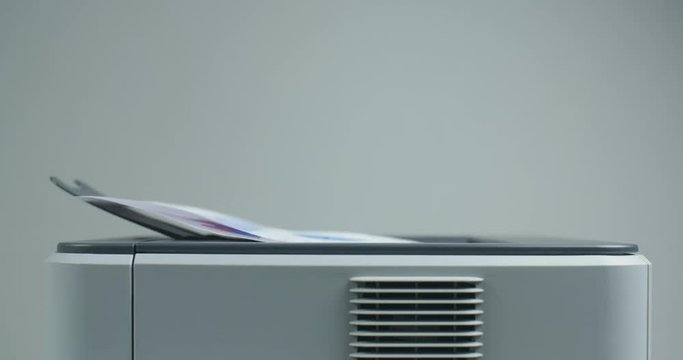 Financial documents coming out of an office printer, detail shot with very shallow depth of field.