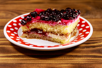 Tasty cheesecake with black currant on wooden table