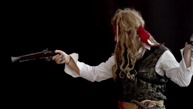 an adult man in a pirate costume holding a gun and aiming looking forward