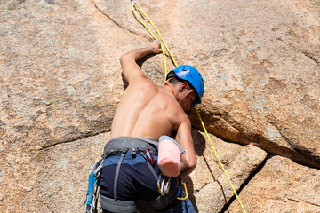 Close up of shirtless male climber climbing mountain wall on amazing sunny day 