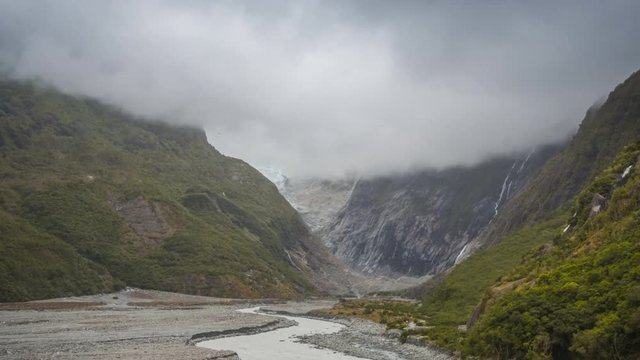 Impressive Franz Josef glacier in New Zealand appearing in mountains as the clouds clear out. Timelapse video.