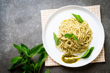 spaghetti with pesto sauce, olive oil and basil leaves.
