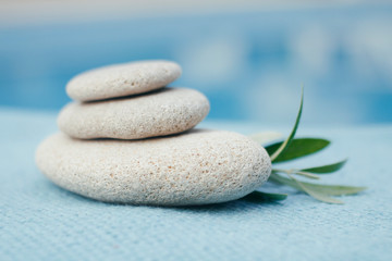 Fototapeta na wymiar Zen stones tower. White spa stones with leaves on blurred blue background. 