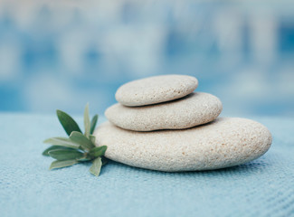Fototapeta na wymiar Zen stones tower. White spa stones with leaves on blurred blue background. 