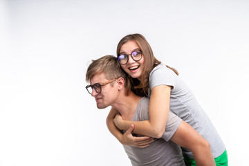 Education, funny people and joke concept - a young woman jumped on a back of man. They are happy