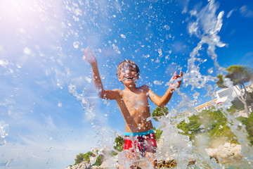 Happy boy splashing water while playing at seaside © Sergey Novikov