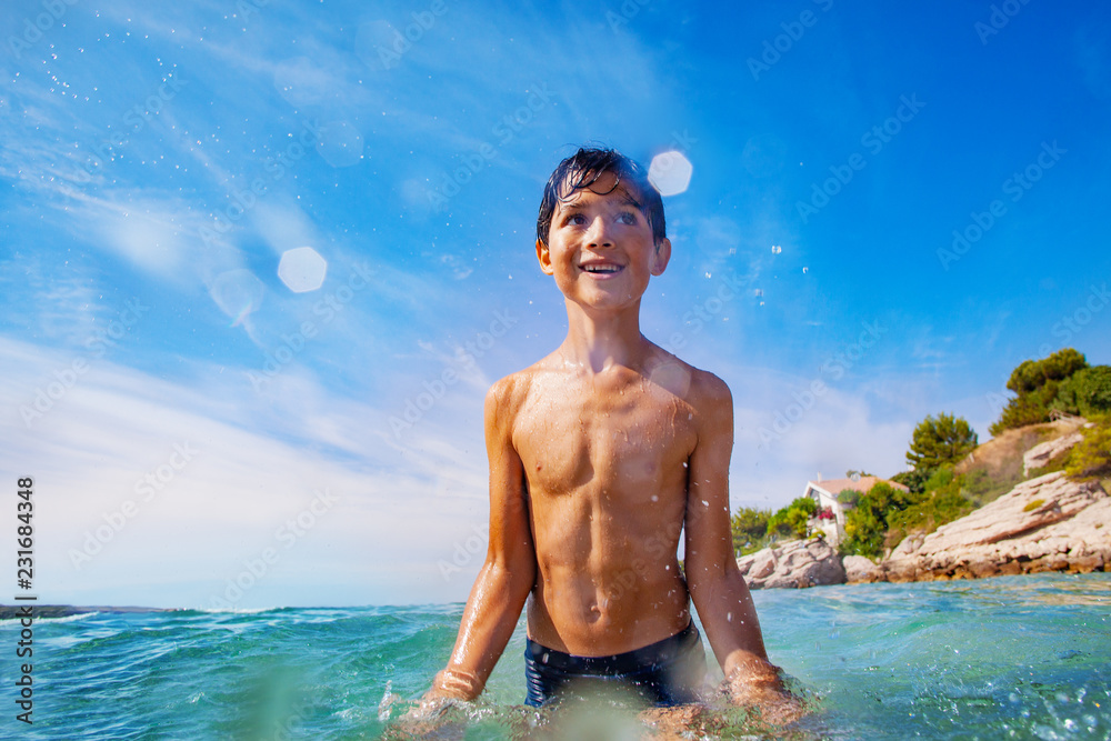 Wall mural cheerful boy playing in water at the seaside