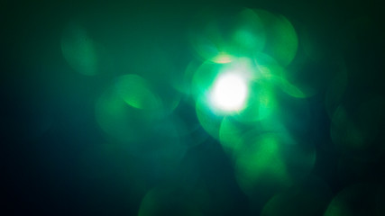 Green bokeh background, dark. Abstract Holiday Light Rays.