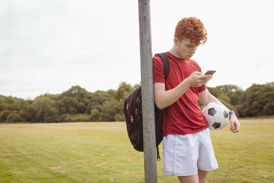 Football player using mobile phone in the field