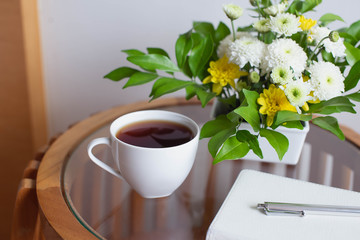 Book, cup of tea and flowers on the wooden table. Morning