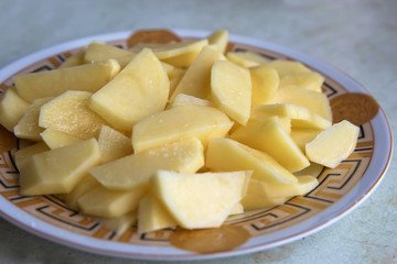 Uncooked cubical yellow potatoes on a chopping board. In the chopped potato plate . Sliced, peeled raw potatoes on a board . 