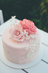 Pink wedding cake with frosting and sugar roses close up