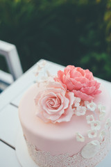 Pink wedding cake with frosting and sugar roses close up
