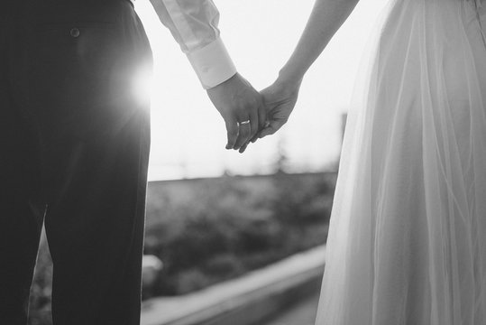 Wedding couple hold their hands close up monochrome