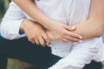 Bride crosses arms on a groom close up