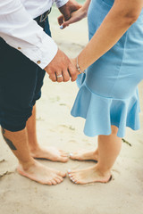Couple stand on the sand and hold their hands