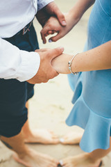 Couple stand on the sand and hold their hands