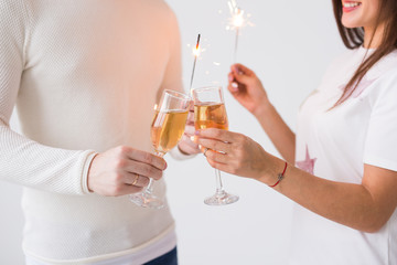 Valentine's Day concept - Close up of happy smiling cheerful attractive couple celebrating with glasses of champagne and sparklers on white background