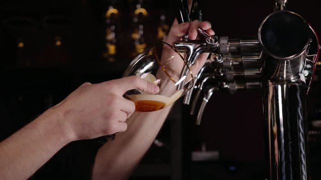 Hand of bartender pouring a large lager beer in tap in a restaurant or pub.