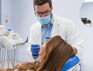Dentist examining woman with dental equipments