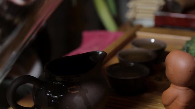 The action of traditional Chinese tea ceremony. Pouring tea from covered bowl in a cup. Wooden tea board on the background.
