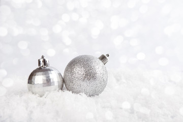 Silver Christmas balls on the snow with shiny background.